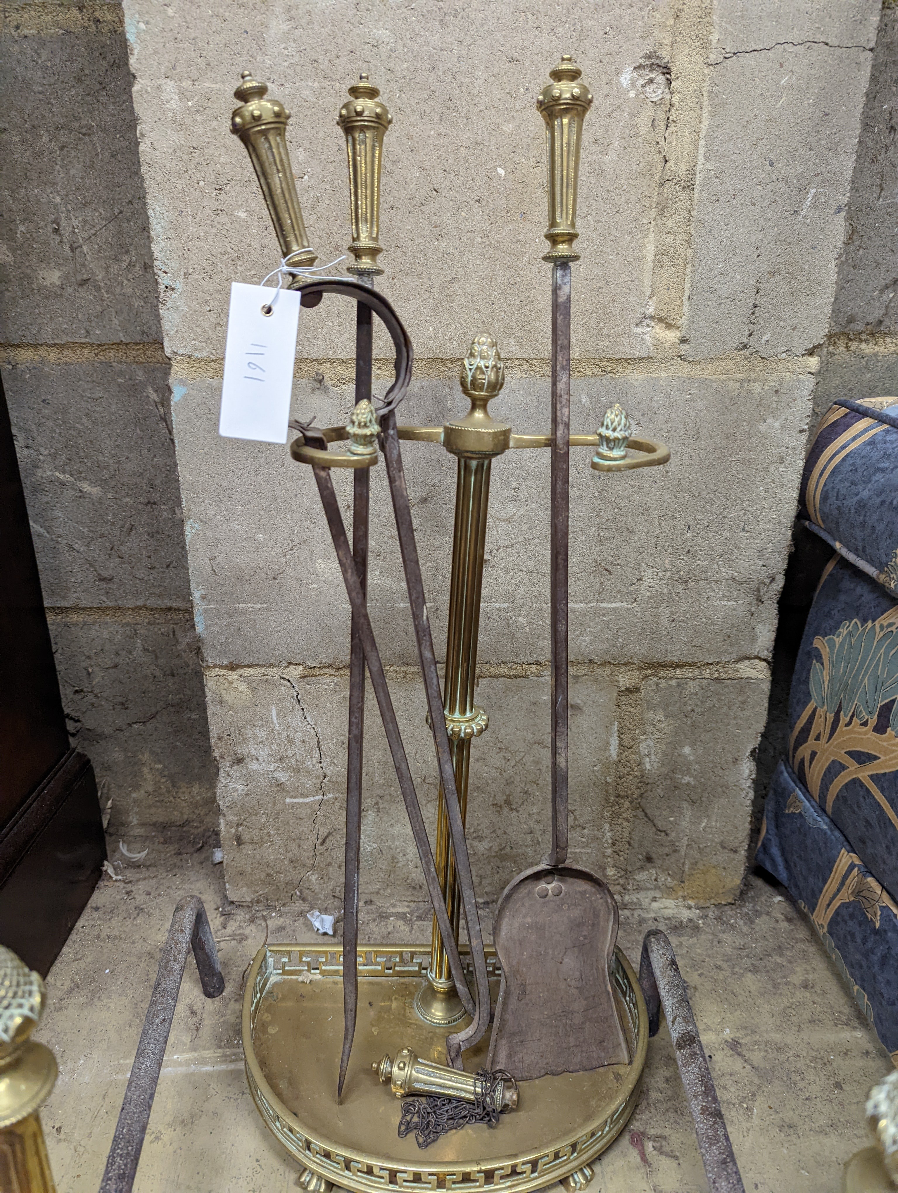 A Regency brass fire curb, a set of five implements and a pair of dogs